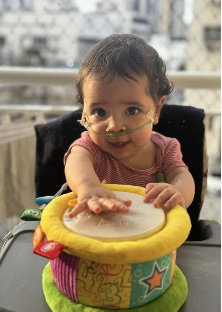 Gabriel, 1 an, sous lunettes nasales d'oxygène, joue du tambourin